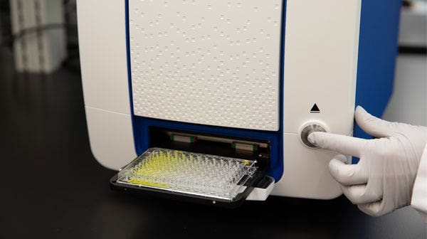Mano che preme il pulsante di espulsione del sistema SpectraMax Mini